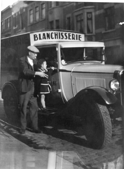 Photographie d'archive : une camionnette de livraison de la blanchisserie et son chauffeur, dans une rue pavée de Bruxelles